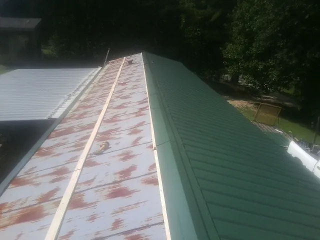 Old rusted panels beside newly installed green metal roofing — Wind Damage Roof Repair by Roofing Brothers in Wilmington