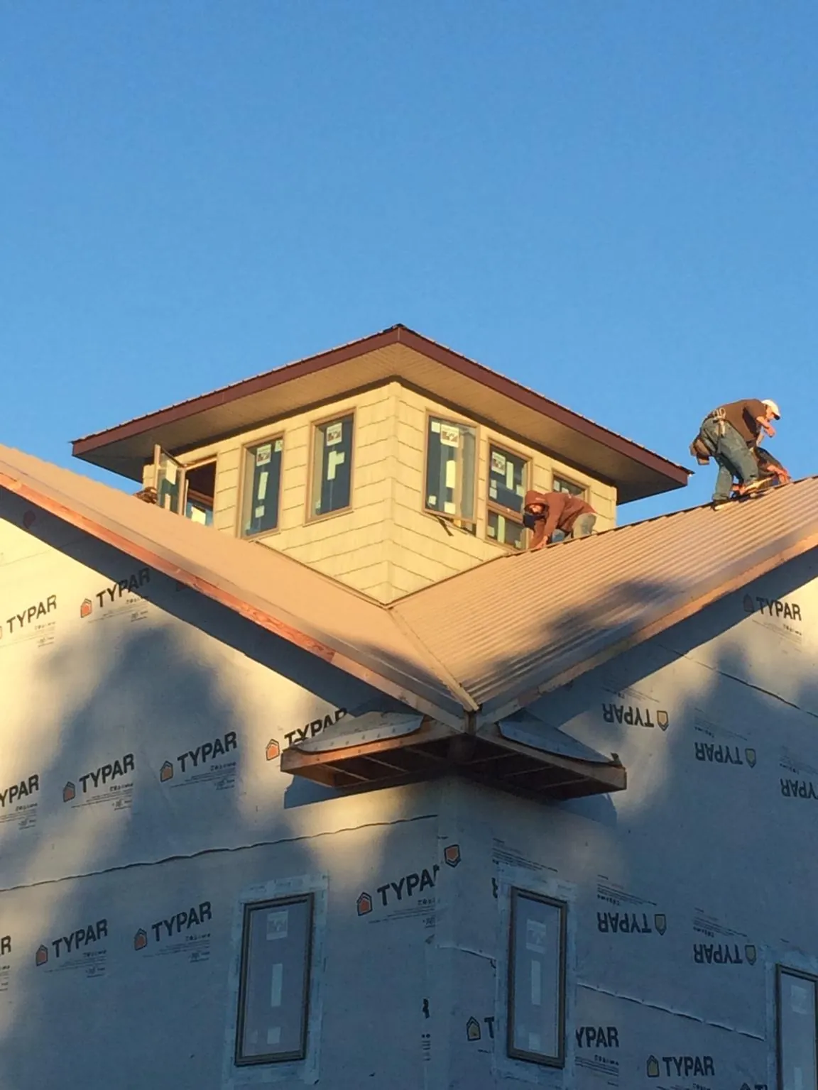 Roofers working around a rooftop cupola on a new metal roof at sunset — Roof Waterproofing in Wilmington by Roofing Brothers